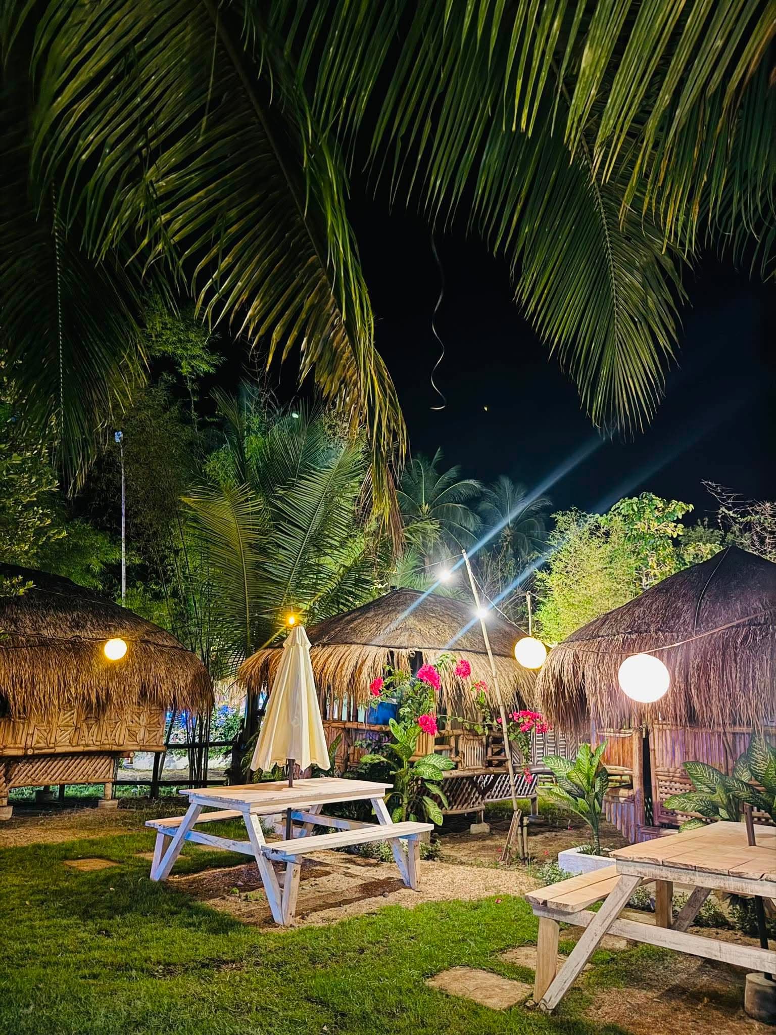 Bahay kubo lit up against the treeline at night